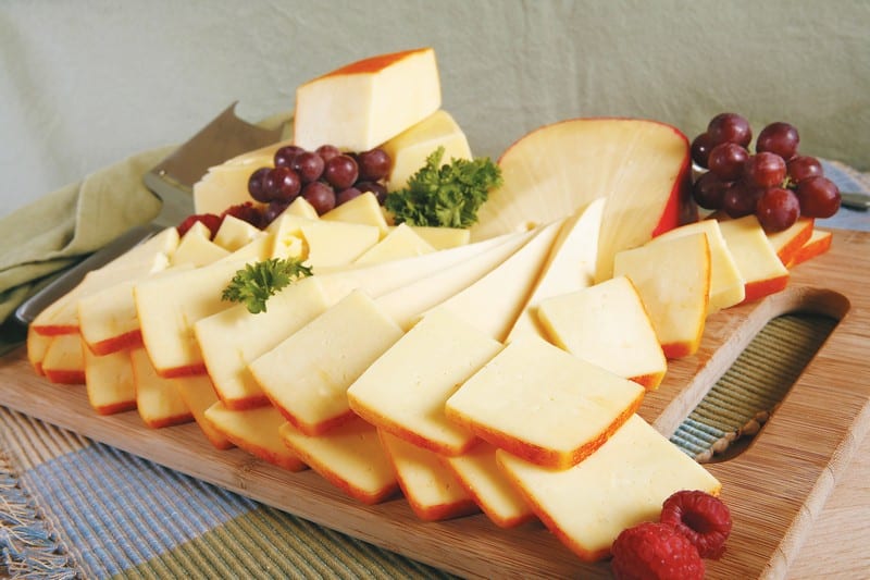 Sliced Muenster Cheese with Grapes and Garnish on Wooden Board Food Picture