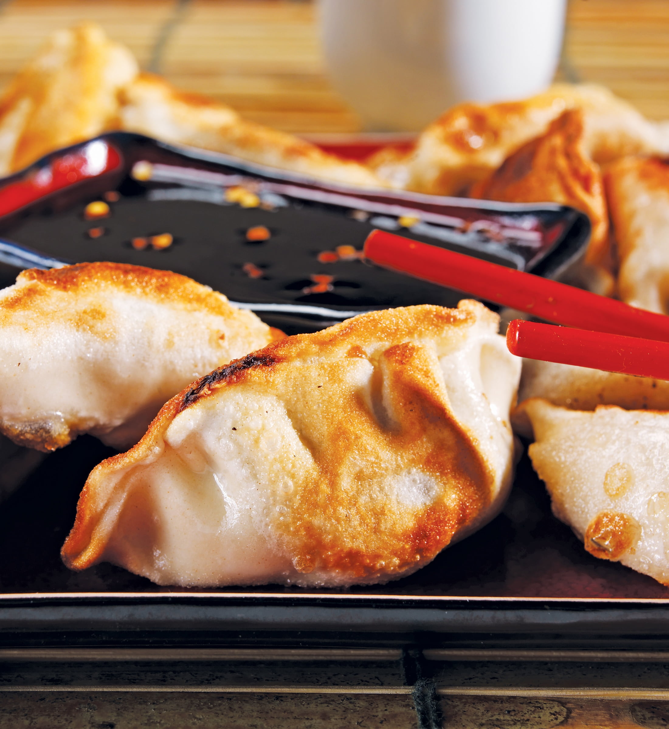Potstickers on Black Plate with Red Chopsticks Food Picture